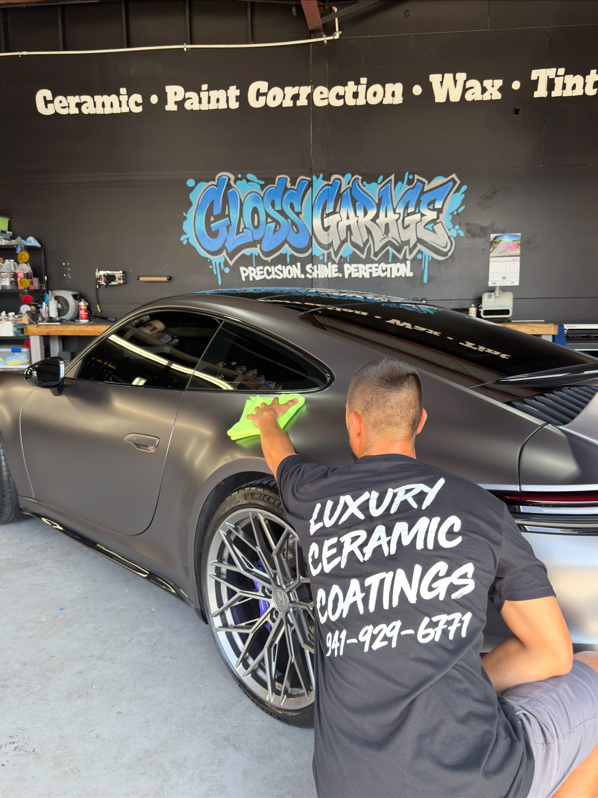 Cody giving the wrapped Porsche 911 a final wipe-down under the Gloss Garage mural
