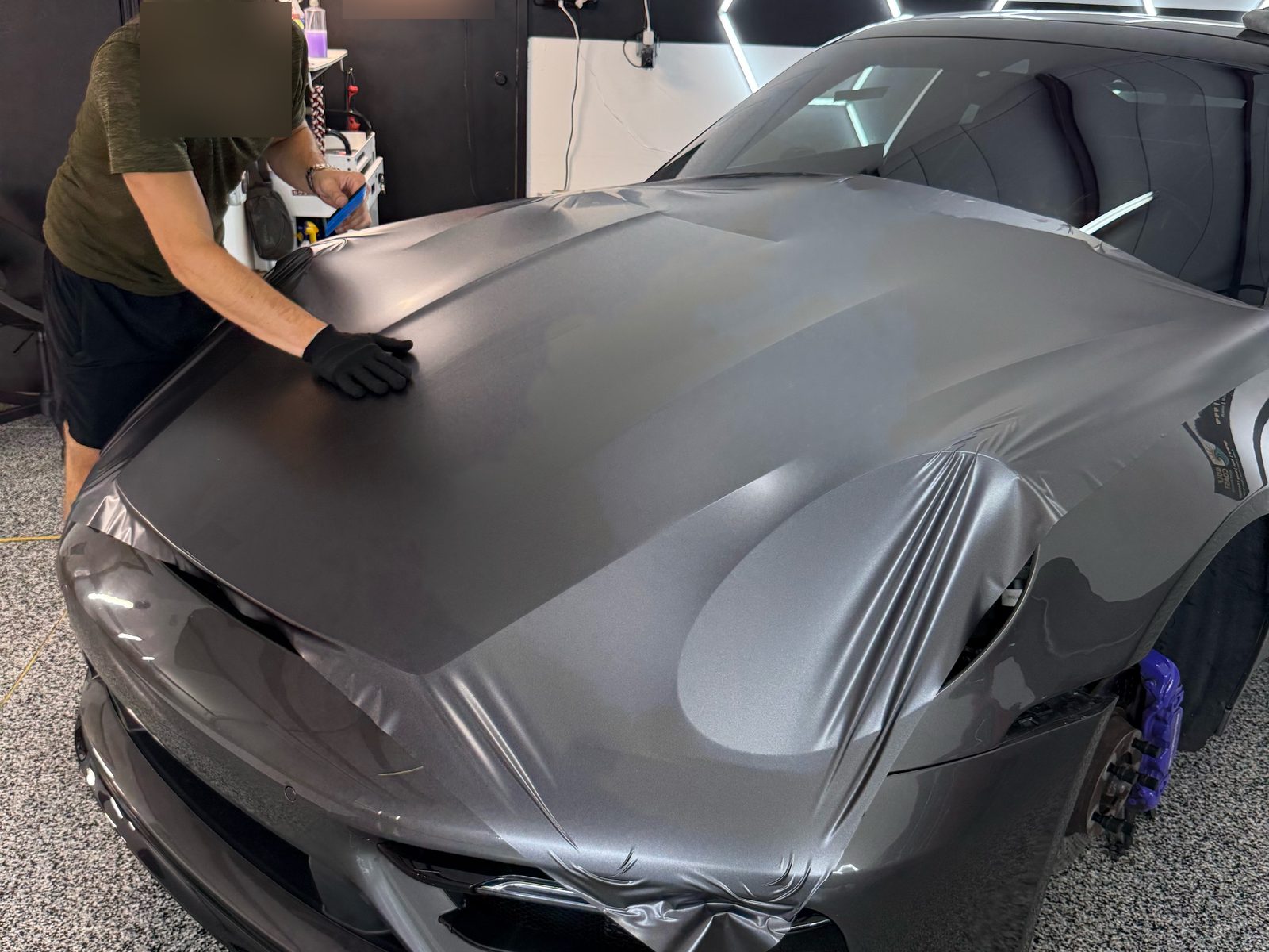 Installer laying satin gray vinyl on the 911 hood